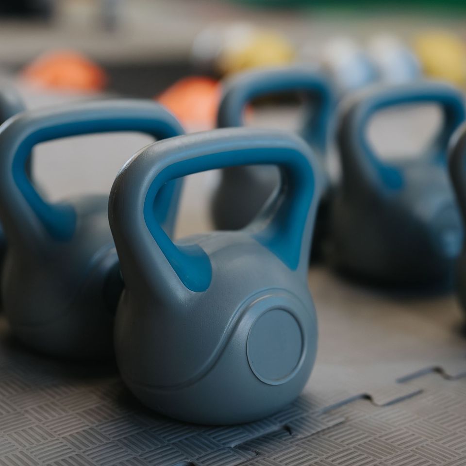 Blue-gray kettlebells lined up on a gym mat