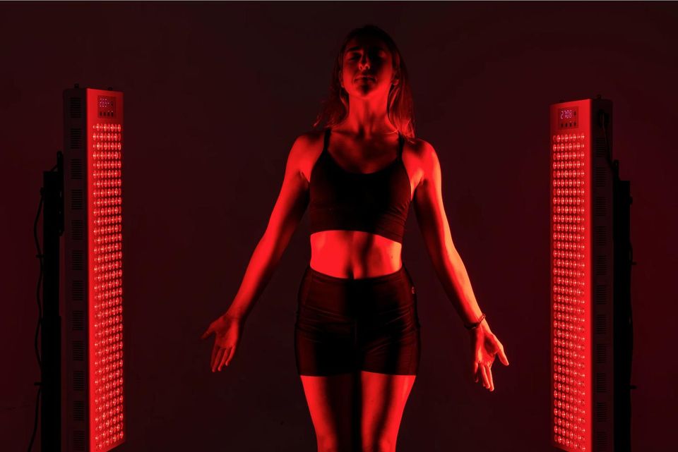 A woman standing between two RedRush red light therapy panels