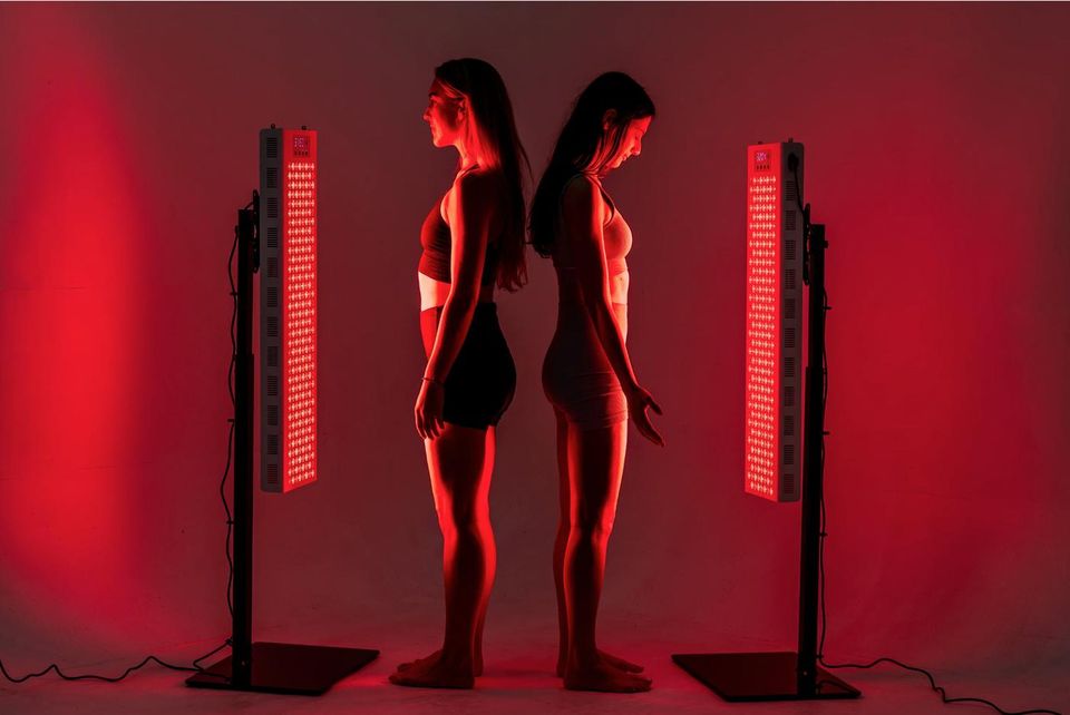 Two women standing between red light panels